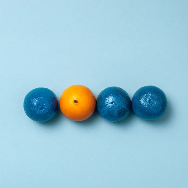 Rangée de 4 oranges dont 3 sont bleues et une seule est orange. Cela traduit la singularité de chaque personne qui est la base de l'accompagnement sous forme de coaching individuel pour reconversion par exemple.